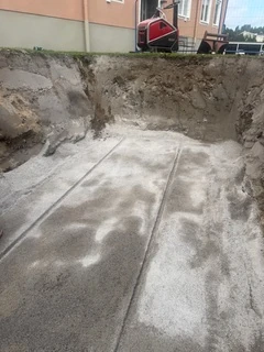 Avjämnad schaktbotten med bärlager och fundament för underjordsbehållare